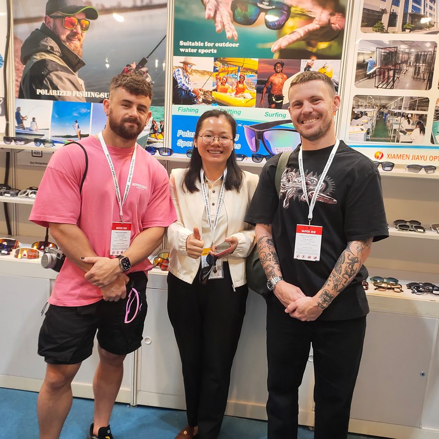 Three people at a Jiayu fair booth in front of floating sunglasses posters