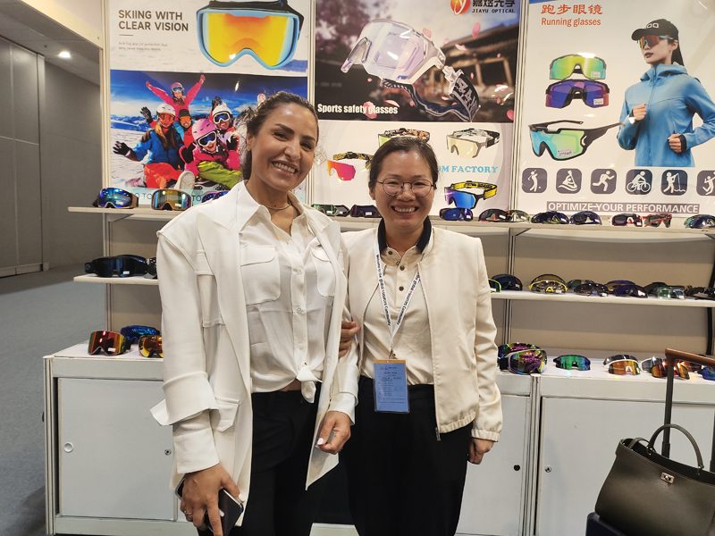 Two Jiayu staff at the April 2024 Global Sources booth with goggles and sunglasses on the wall